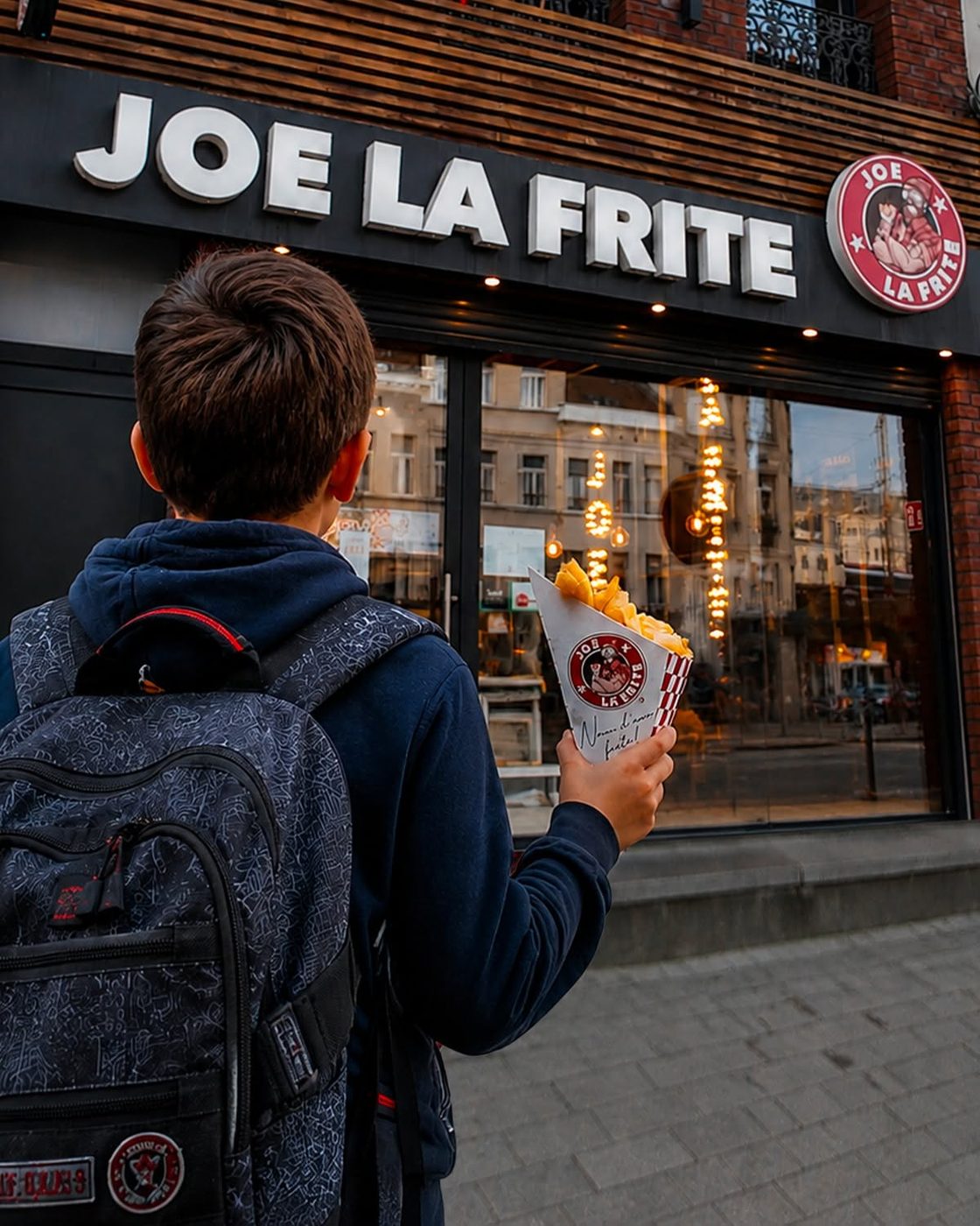 Devanture Joe La Frite à Bruxelles avec un client tenant un cornet de frites